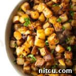 Crispy skillet potatoes garnished with fresh parsley, sitting in a white bowl.