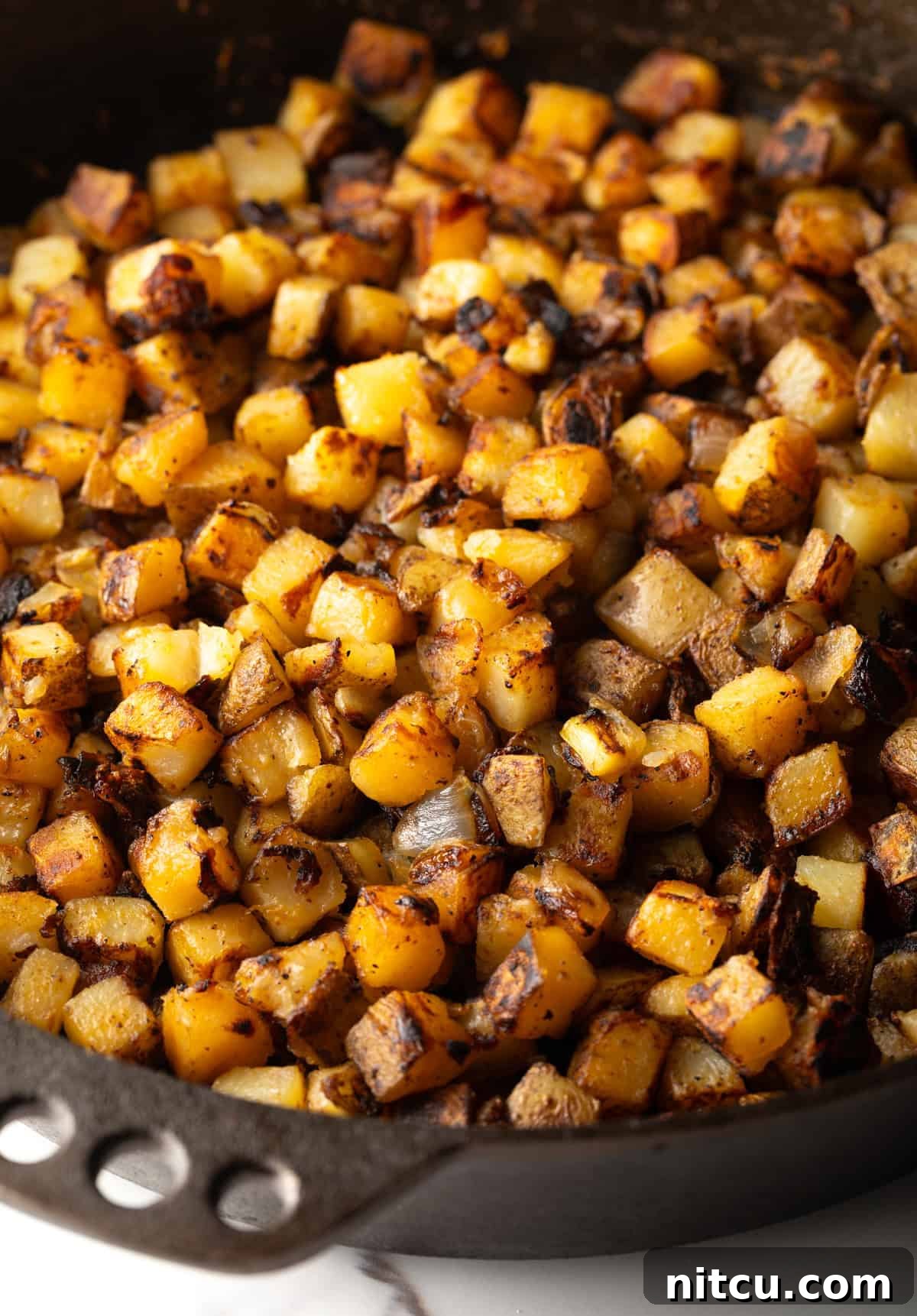 Crispy skillet fried potatoes in a black skillet.