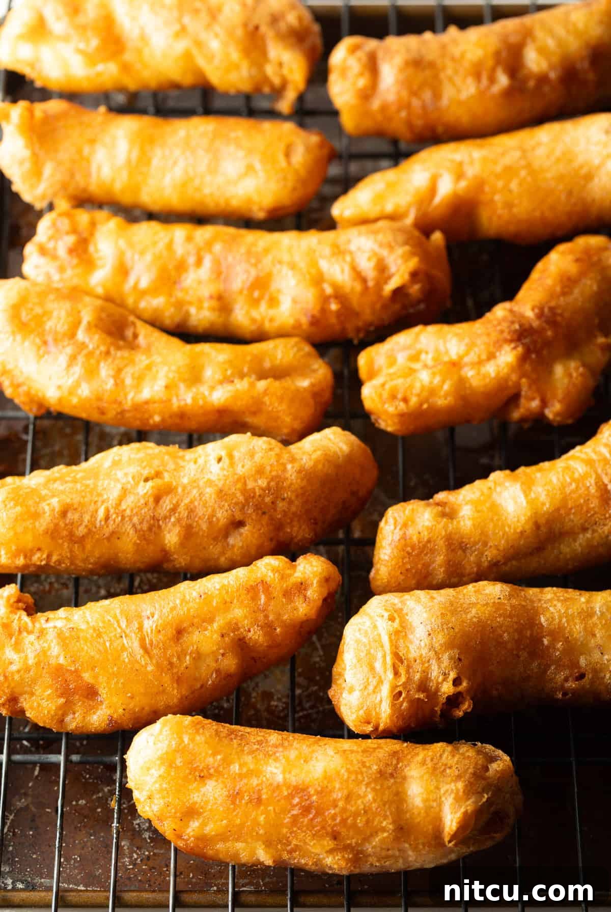 Crispy fried fish pieces sitting on a draining rack.