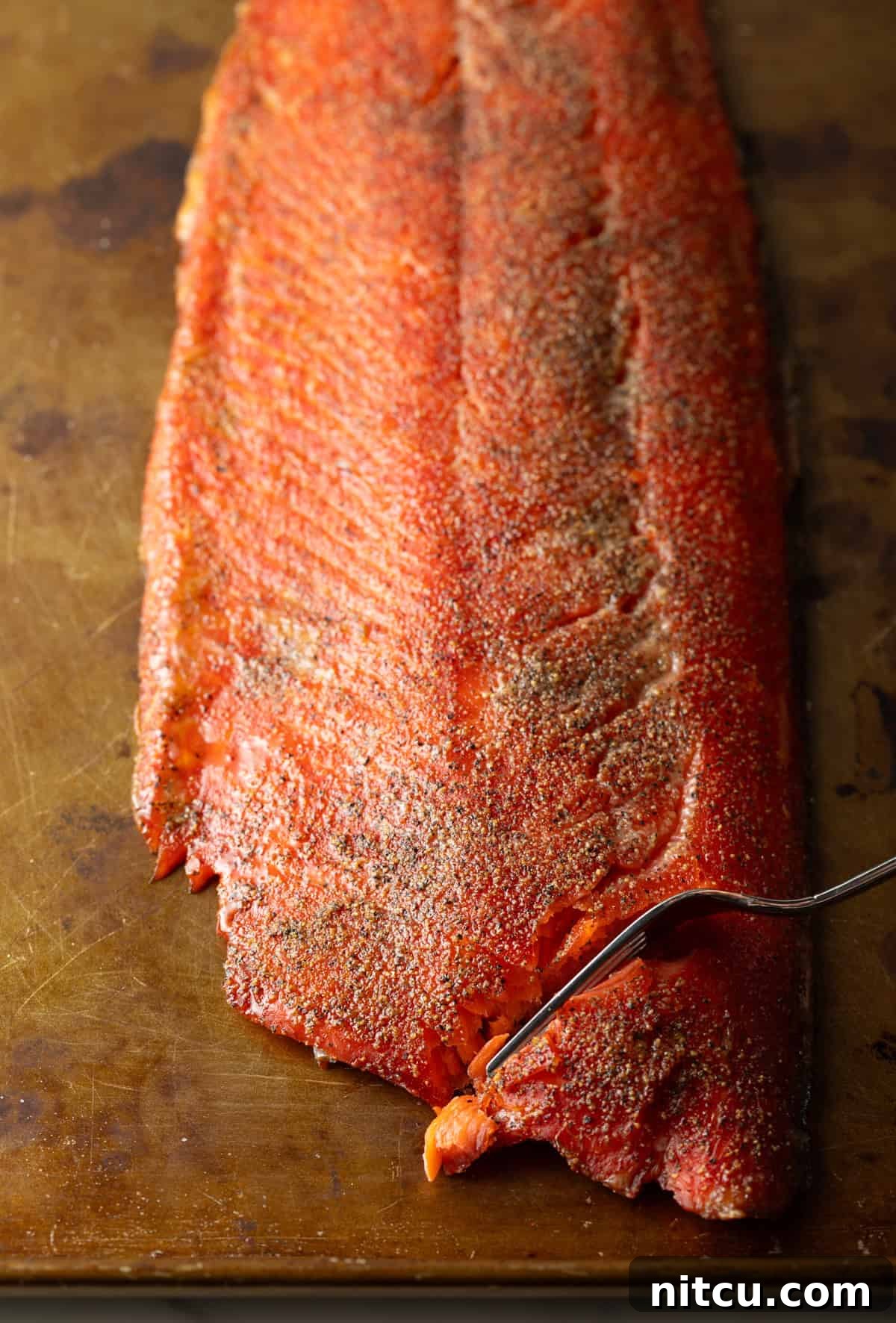 A cold smoked salmon recipe with a fork that is cutting a piece off.