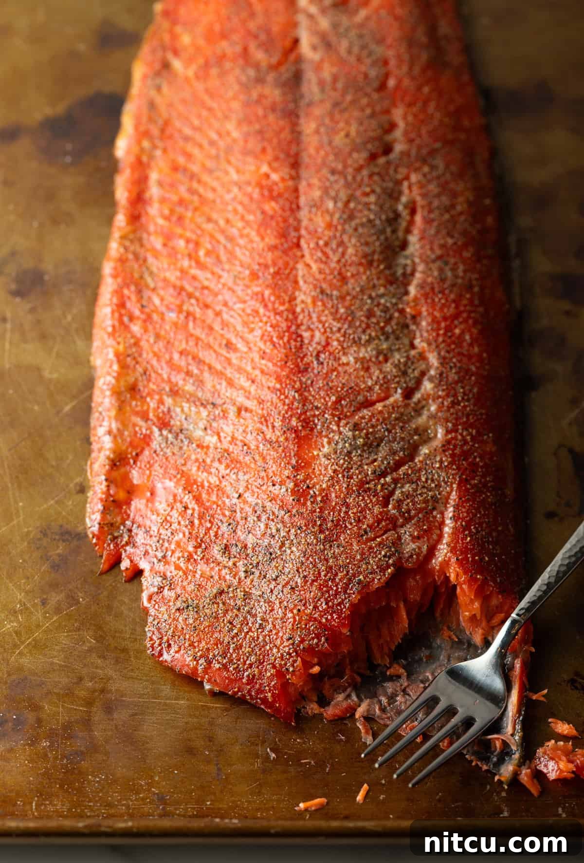 A a whole cold smoked salmon recipe with a fork that is cutting a piece off.