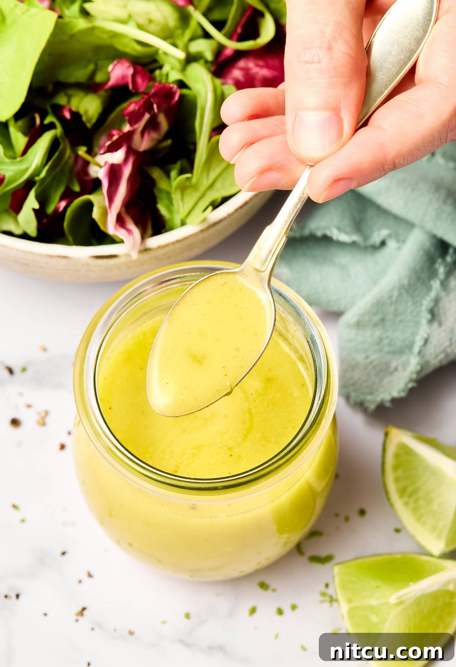 Lime Vinaigrette Recipe with Garlic in a jar, with a spoon lifting the sauce.