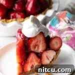 A slice of easy no-bake strawberry pie topped with whipped cream, sitting on a white plate.
