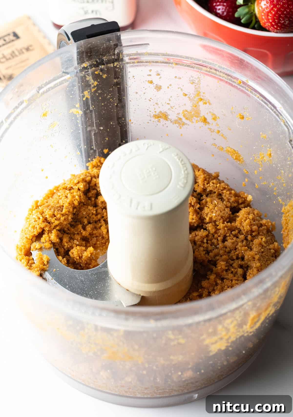 Ginger snap cookies are being pulsed in a food processor to make a crust for a strawberry pie recipe.