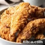 Crispy Deep-Fried Chicken Tenders Recipe That Delivers 11 Crispy deep fried chicken tenders sitting in a white bowl.