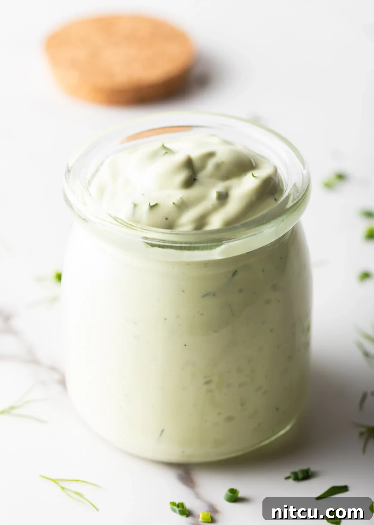 A glass jar filled with copycat Chick Fil A avocado lime ranch dressing.