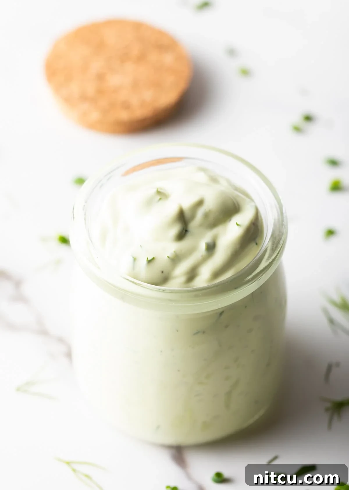 Glass jar of green creamy dressing.